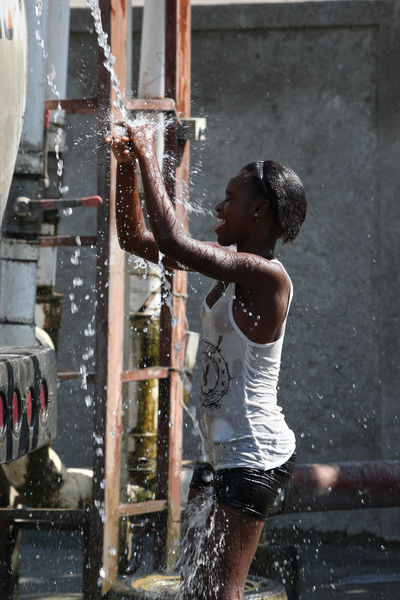 Girl cooling off at water truck station
