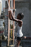 Girl cooling off at water truck station - © Adam Stoltman. All rights reserved.