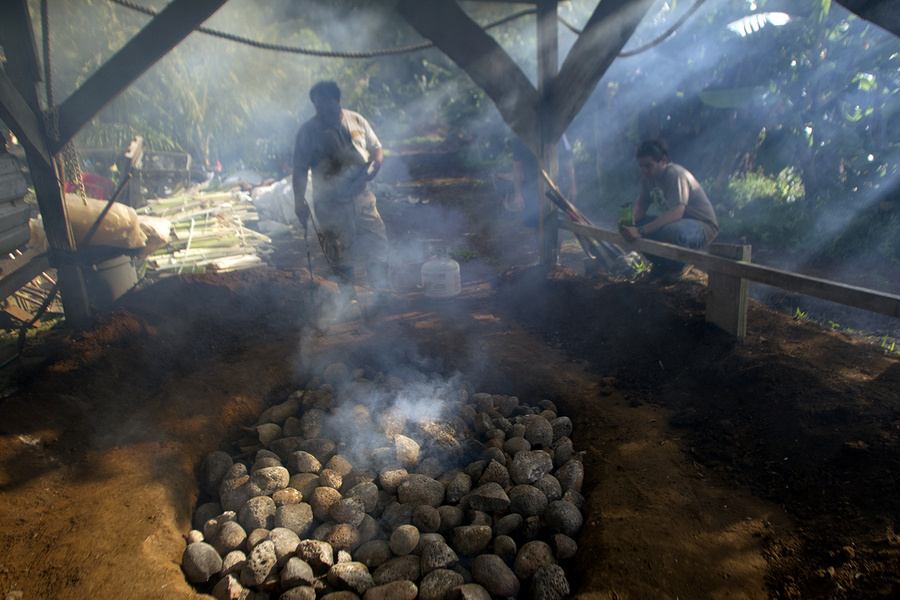A fire tender finishes lighting an imu, a traditional Hawaiian oven of wood and stones in an earthen pit that takes community members all day to prepare. When ready, food is placed inside the imu and cooked overnight. In Kokua Kalihi Valleys Ehuola Program, children and their families participate in the preparation of the imu to better understand the cultural relationship between health, food, and the land, and to reconnect to important cultural practices. : Capturing Culture : Photography by Adam Stoltman: Sports Photography, The Arts, Portraiture, Travel, Photojournalism and Fine Art in New York