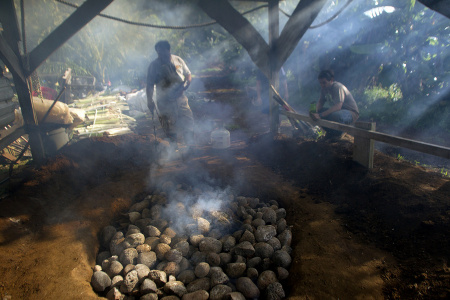 A fire tender finishes lighting an imu, a traditional Hawaiian oven of wood and stones in an earthen pit that takes community members all day to prepare. When ready, food is placed inside the imu and cooked overnight. In Kokua Kalihi Valleys Ehuola Program, children and their families participate in the preparation of the imu to better understand the cultural relationship between health, food, and the land, and to reconnect to important cultural practices.