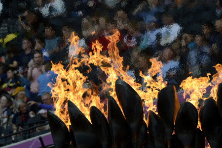 The Olympic flame with spectators at the Olympic Stadium in the background. 